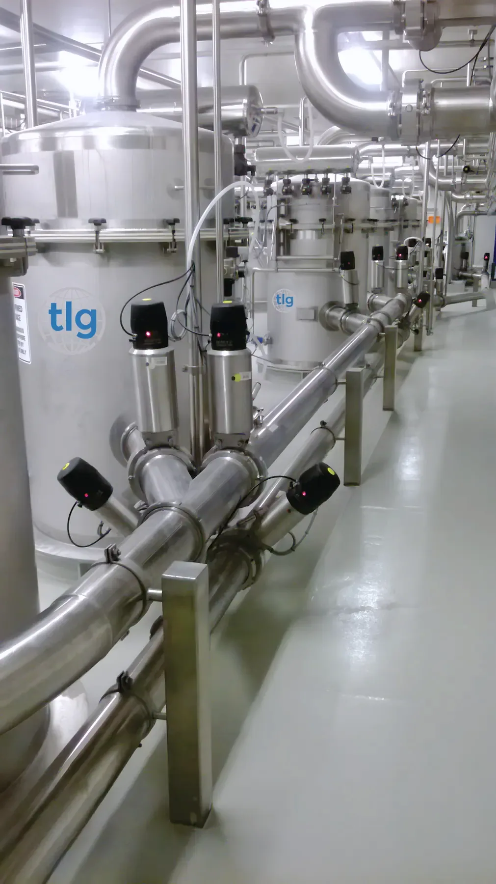 A line of TLG receival vessels and convey pipework down a plant corridor