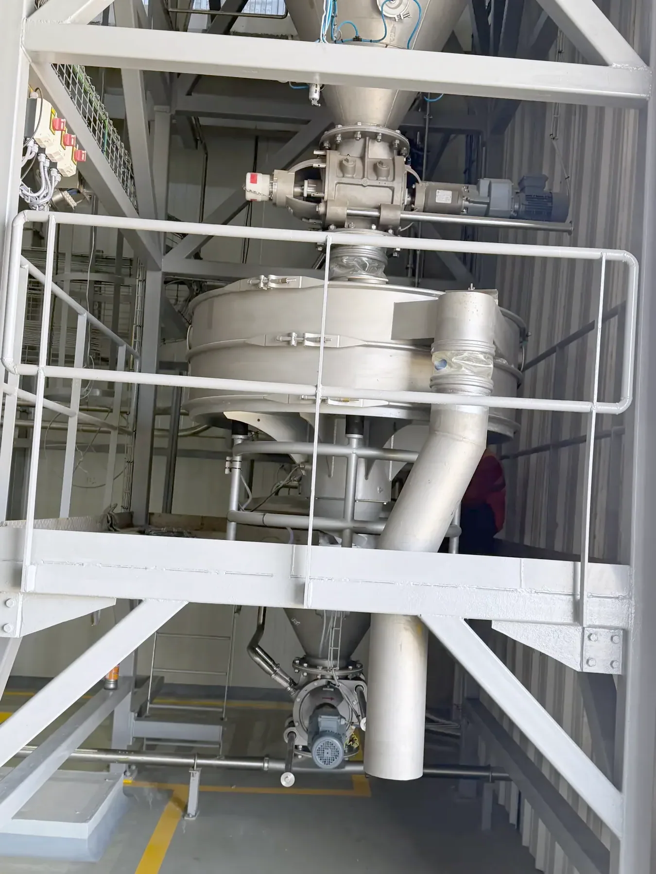 A TLG vibratory sifter and rotary valve on a plant mezzanine, guard rails around the deck