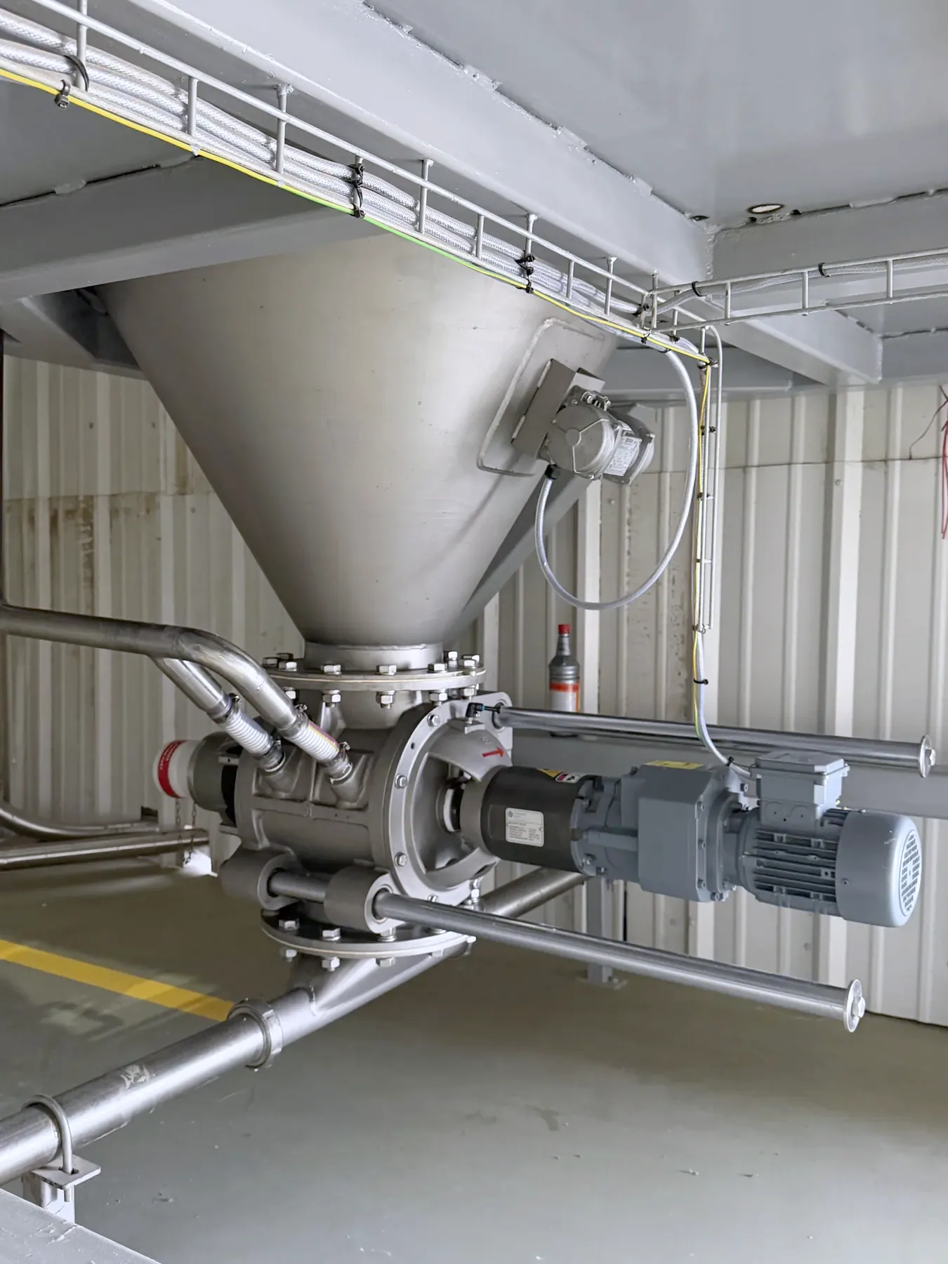 A TLG rotary valve and drive beneath a hopper cone, installed on a convey line