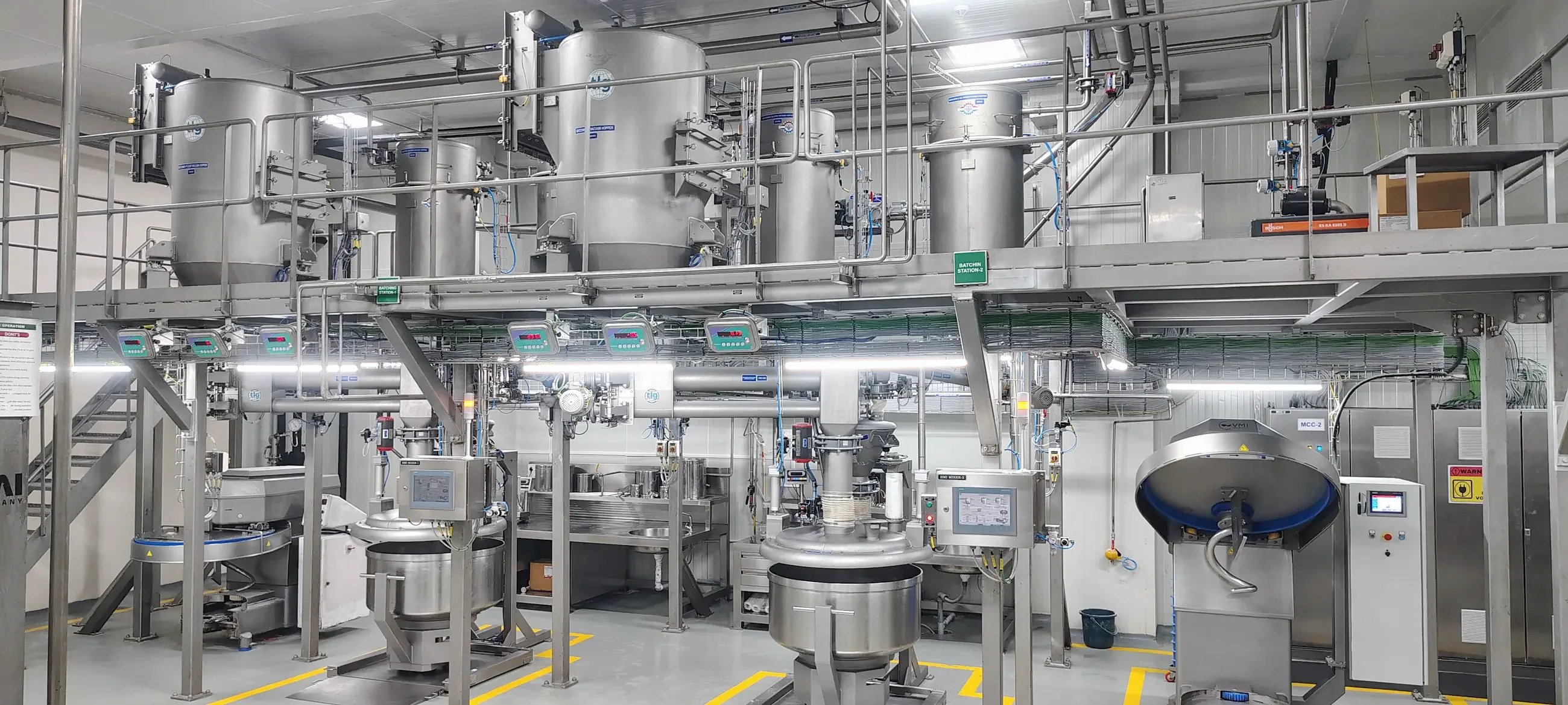 A TLG batching station — vacuum hoppers on the mezzanine feeding weighed mixers on the floor below